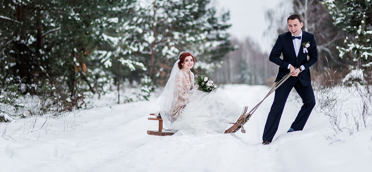 groom pulling his bride on a sled